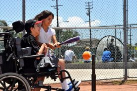 Participant and adult at a tee-ball activity