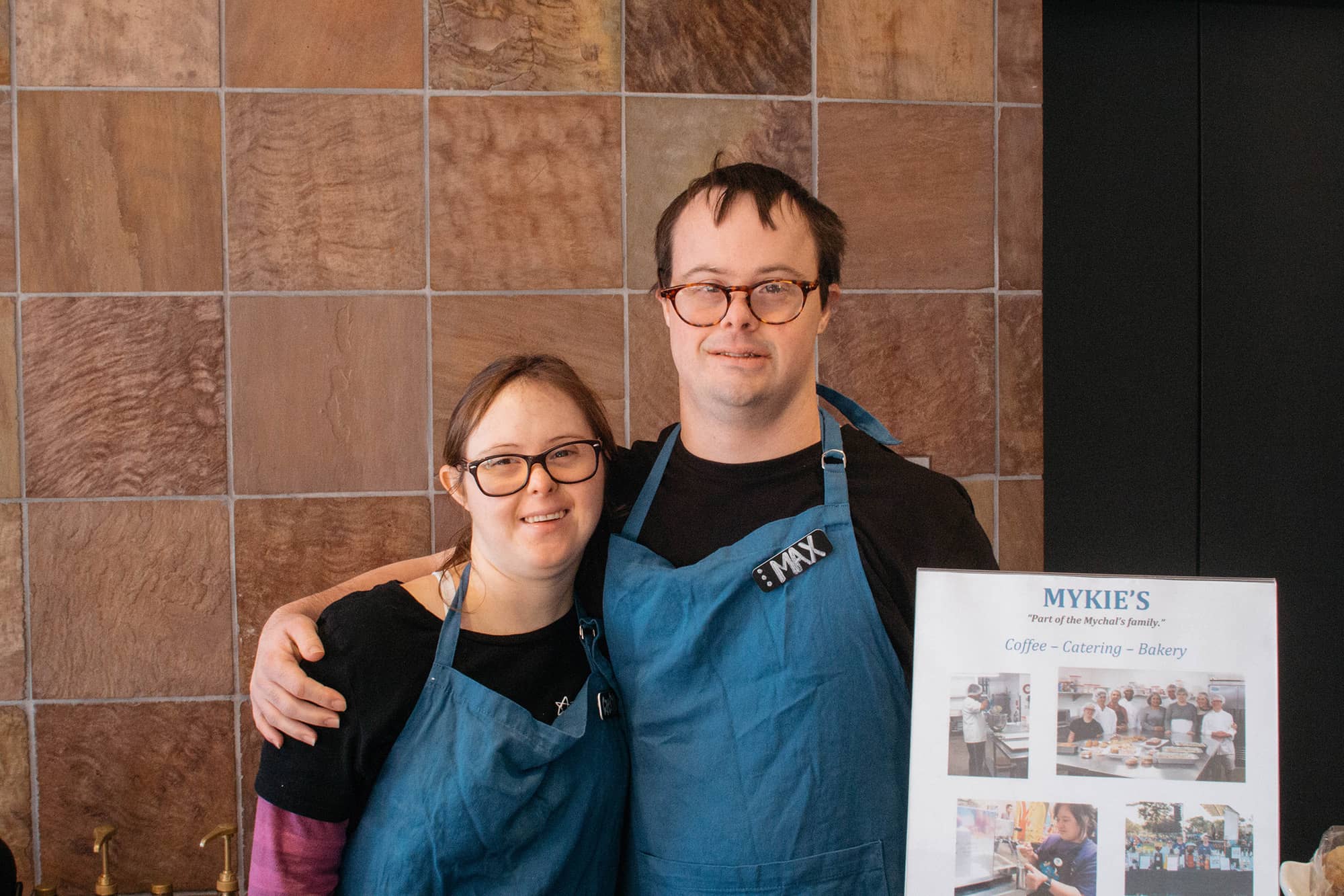 Two people posing with a framed item
